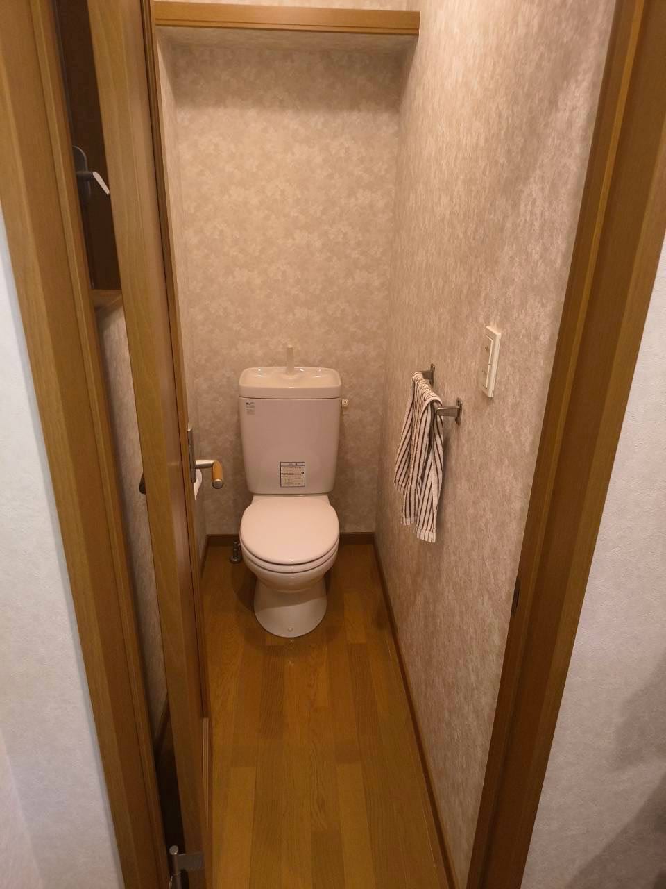 施工前のトイレ。古い便器と、色あせた壁紙が目立つ空間